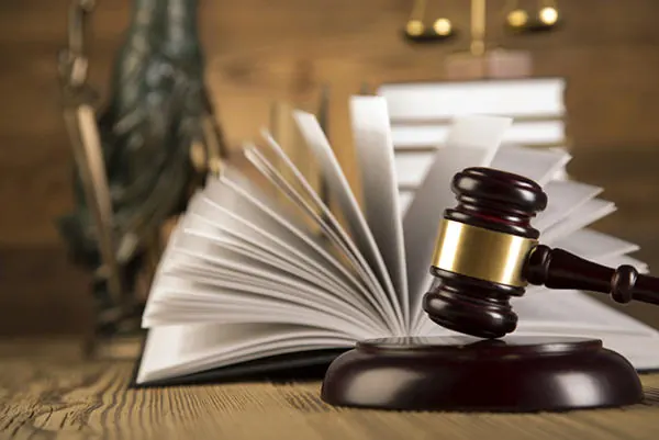 Libro de leyes abierto, mazo de juez y estatua de la justicia